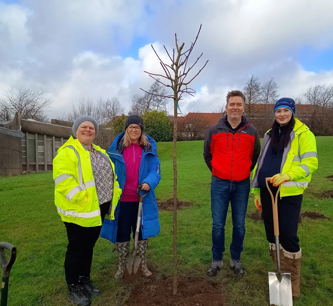 three women and a man planting a tree