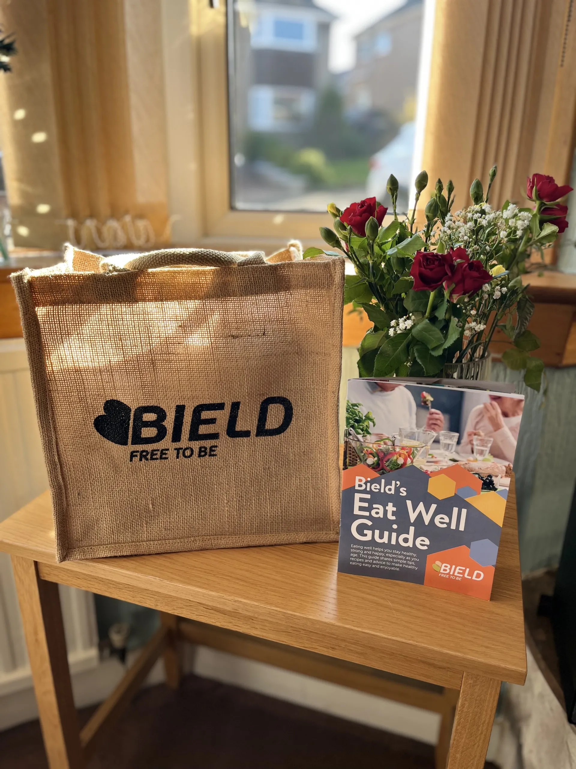 bield free to be tote bag on a table with an eat well guide leaflet