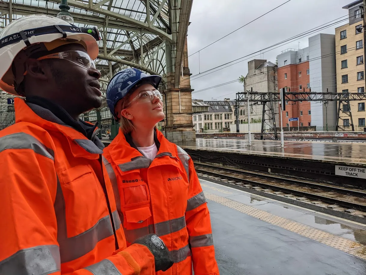 a black man and a caucasian woman in hi-vis jackets and hard hats