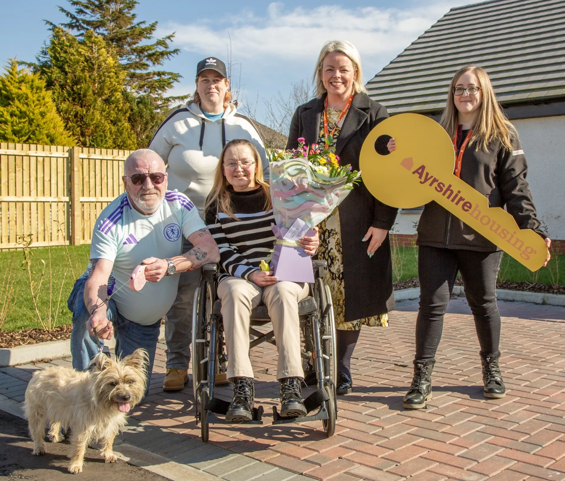 tenants with large key in garden with a dog and a bouquet of flowers