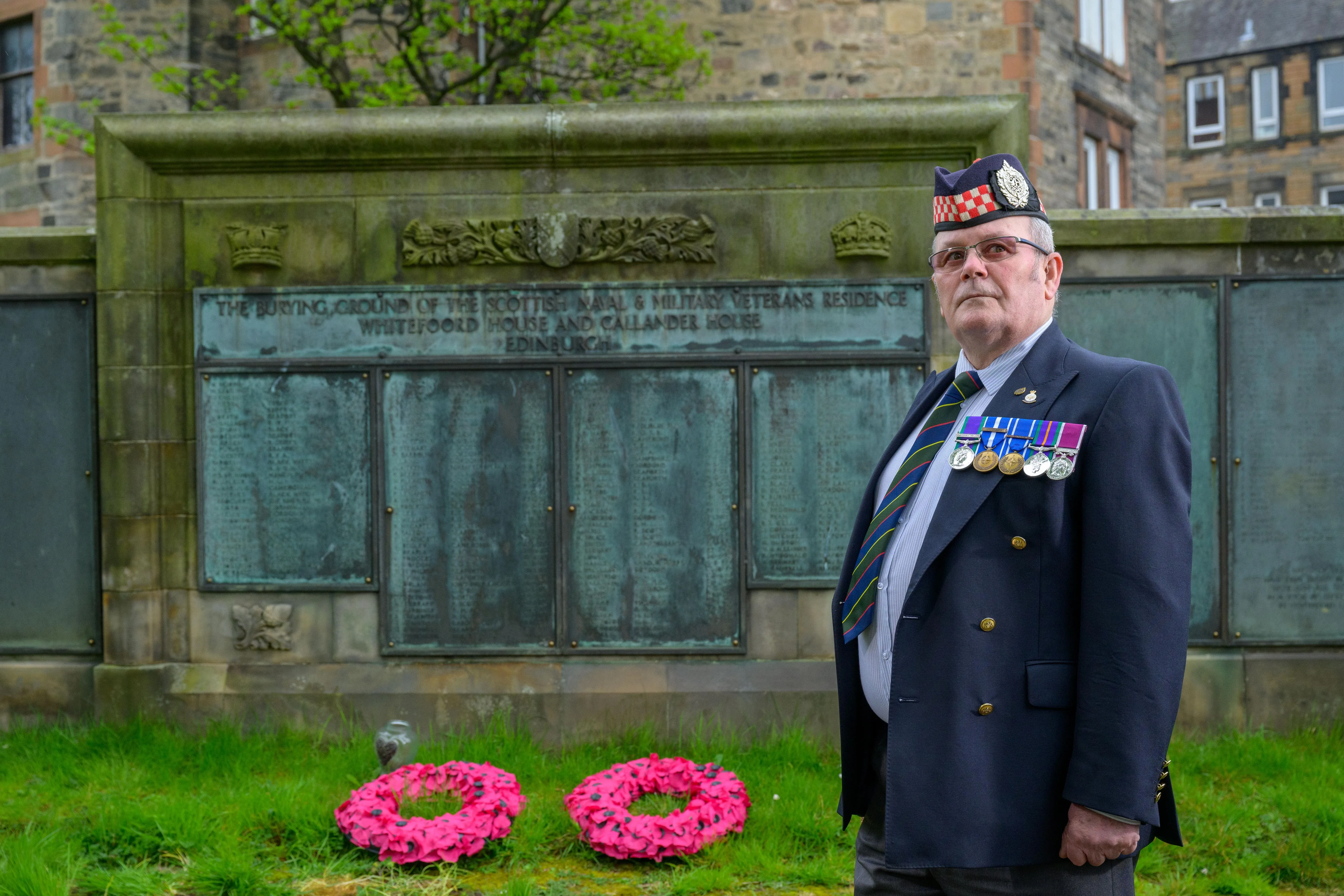 veteran at memorial with two poppy reeves. 