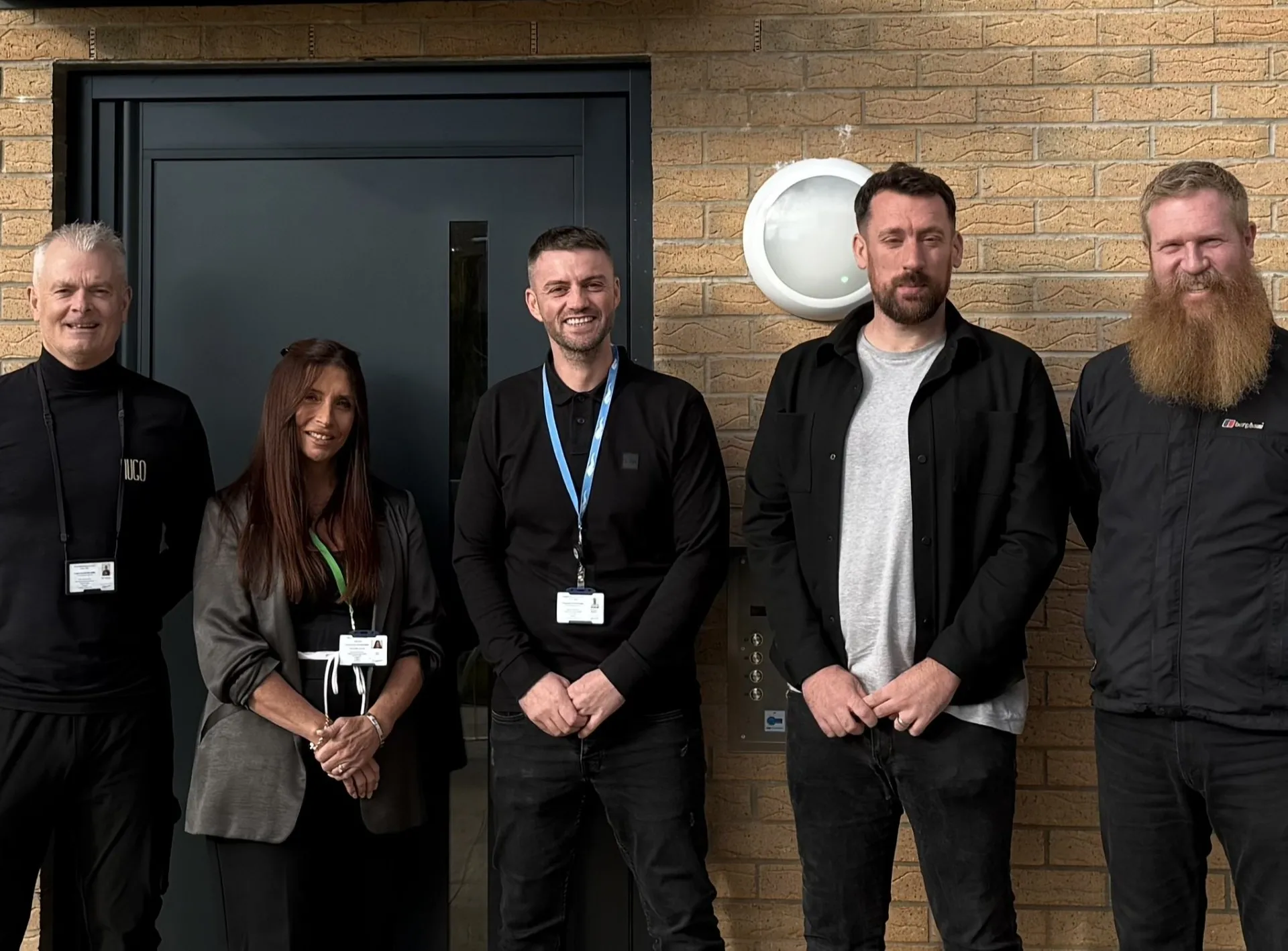 five members of almond housing association staff outside the front door of a house